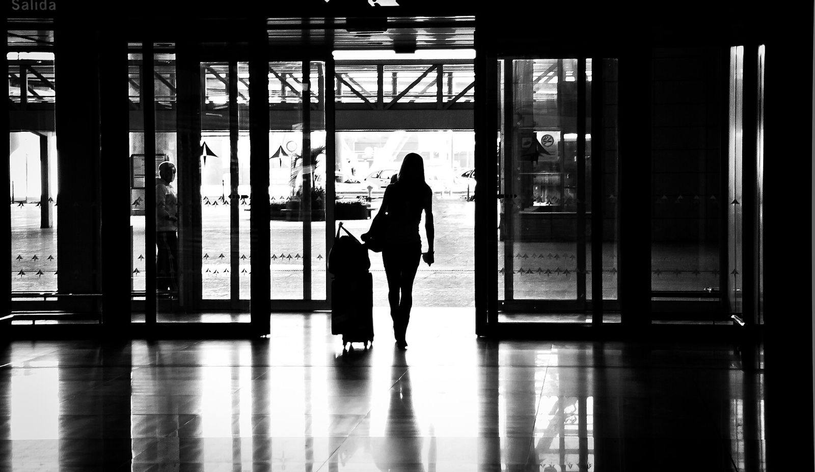 Silhueta de viajante com mala num átrio de aeroporto