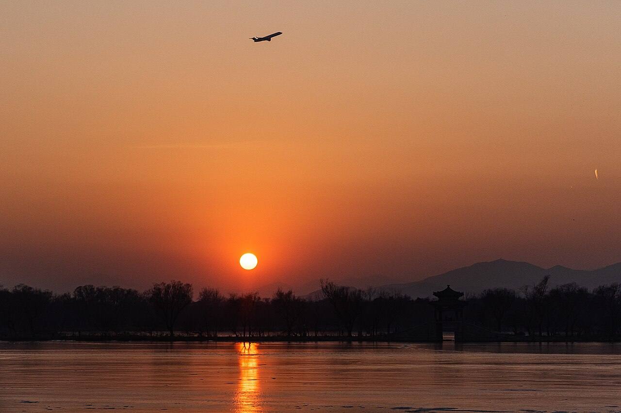 Avião a descolar ao pôr do sol sobre um lago