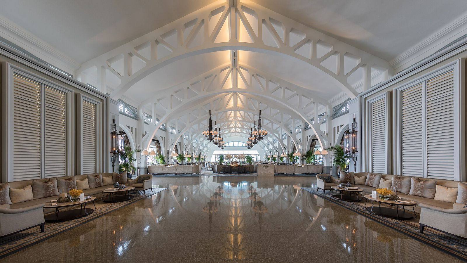 Átrio de hotel com arcos brancos e sofás ao longo da nave